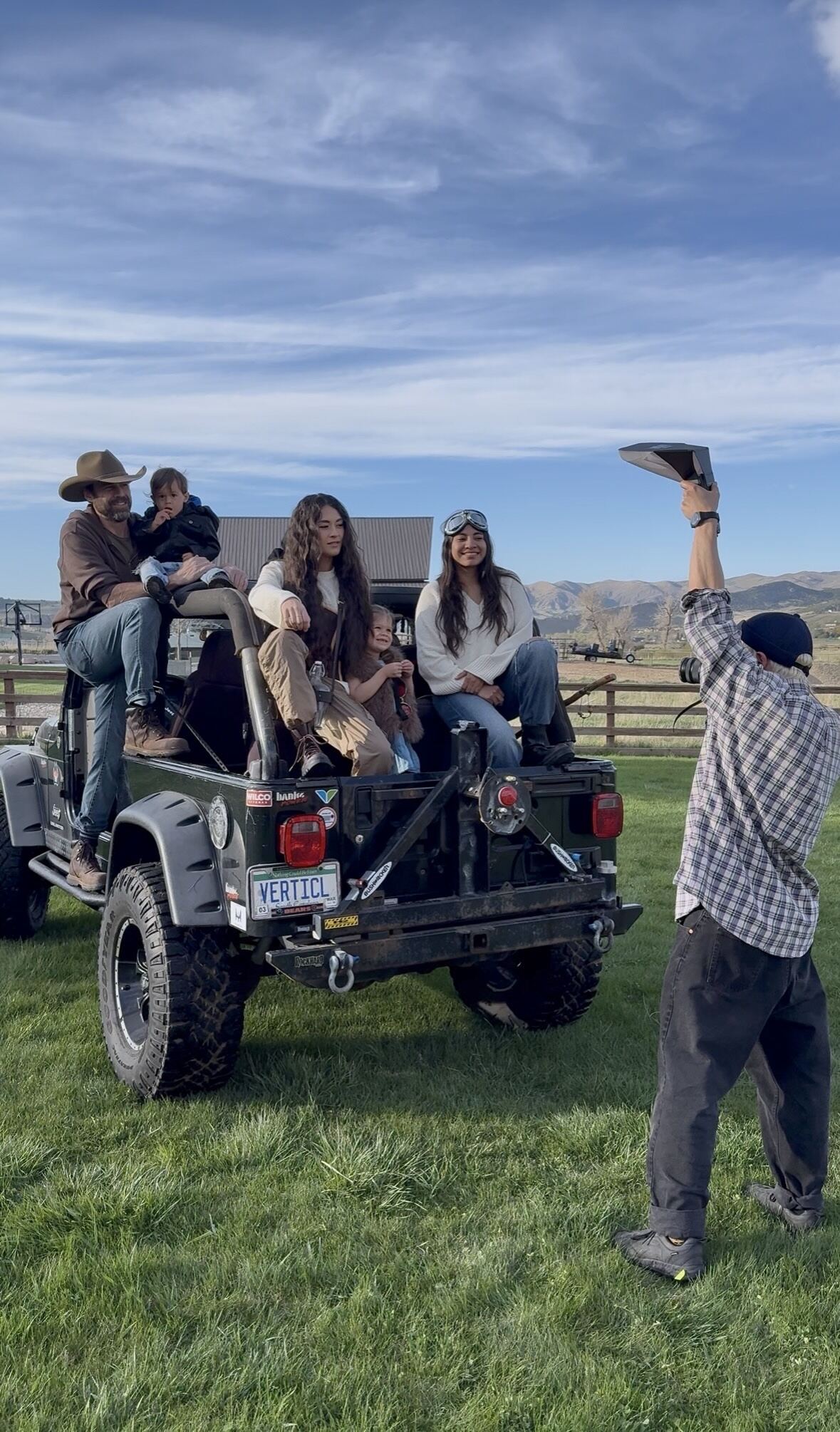 Photographer directing a family seated on an open-top Jeep in a Utah mountain meadow