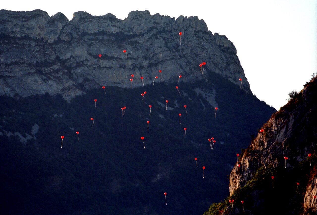 Red balloons floating in front of a rocky mountain cliff