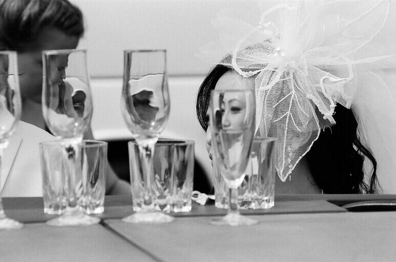 Black and white event photo of champagne glasses and a guest in a bridal veil