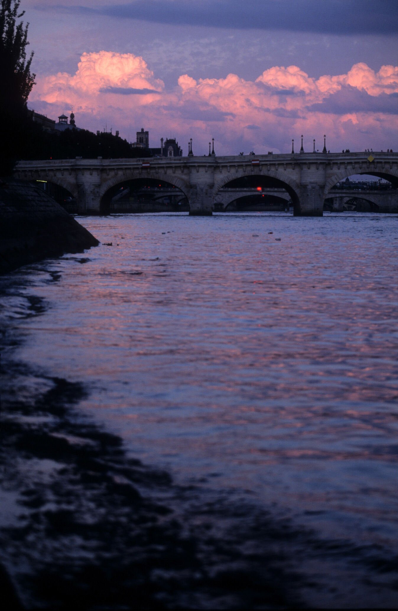 Stone bridge over a river at dusk under pink clouds