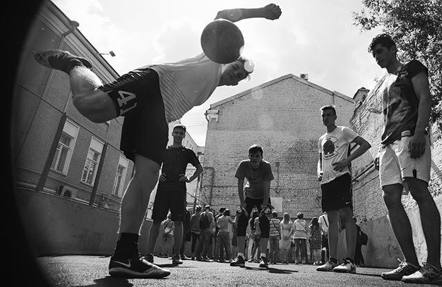 Black and white street football photo of a player kicking the ball overhead