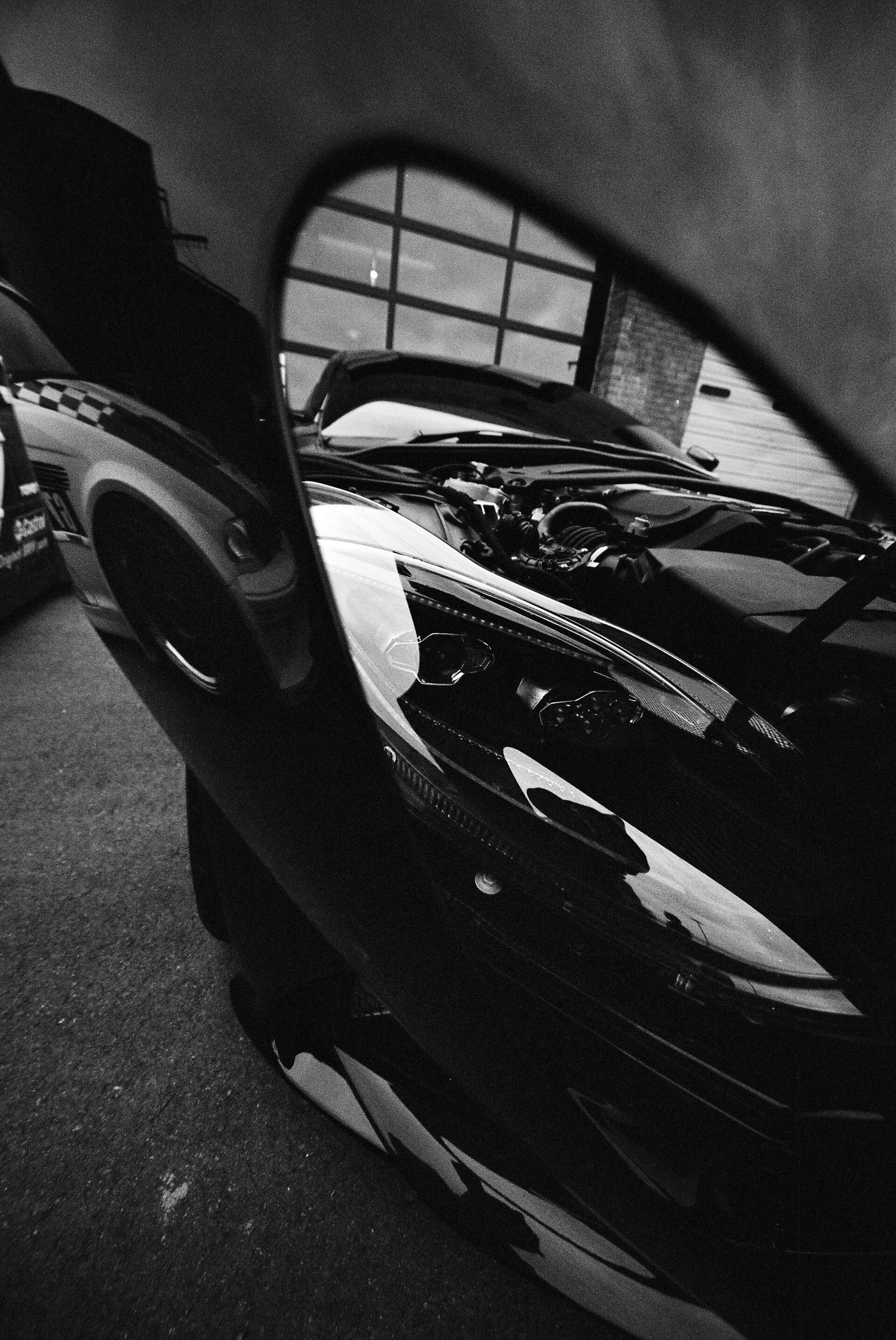Black and white photograph of a sports car parked beneath an arched garage window