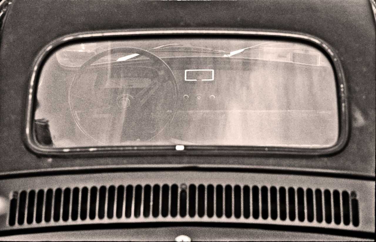 Black and white close-up of a vintage car's rear window